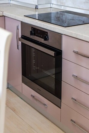 Een keuken met een inbouwoven, een aanrecht en een kast met lades.