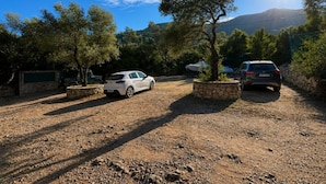 A parking area with two cars, stone planters, and trees. - Ulysse77 - Ocean-View House with Pool & Garden (syvota)