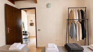 A room with two beds, a clothing rack, and a door leading to another room. - Ulysse77 - Ocean-View House with Pool & Garden (syvota)