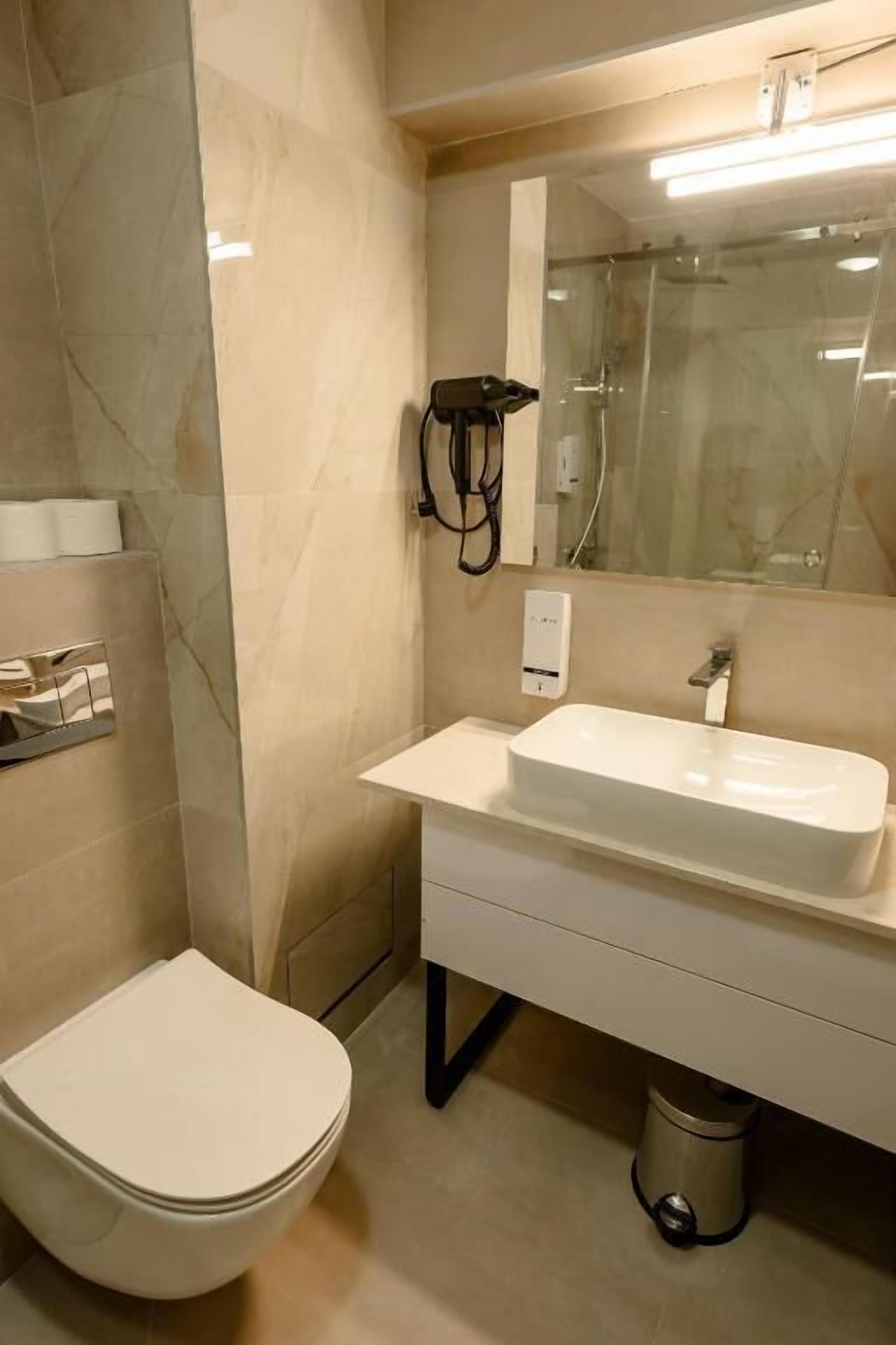 Une salle de bain comprenant des toilettes, un lavabo, un miroir et une cabine de douche.