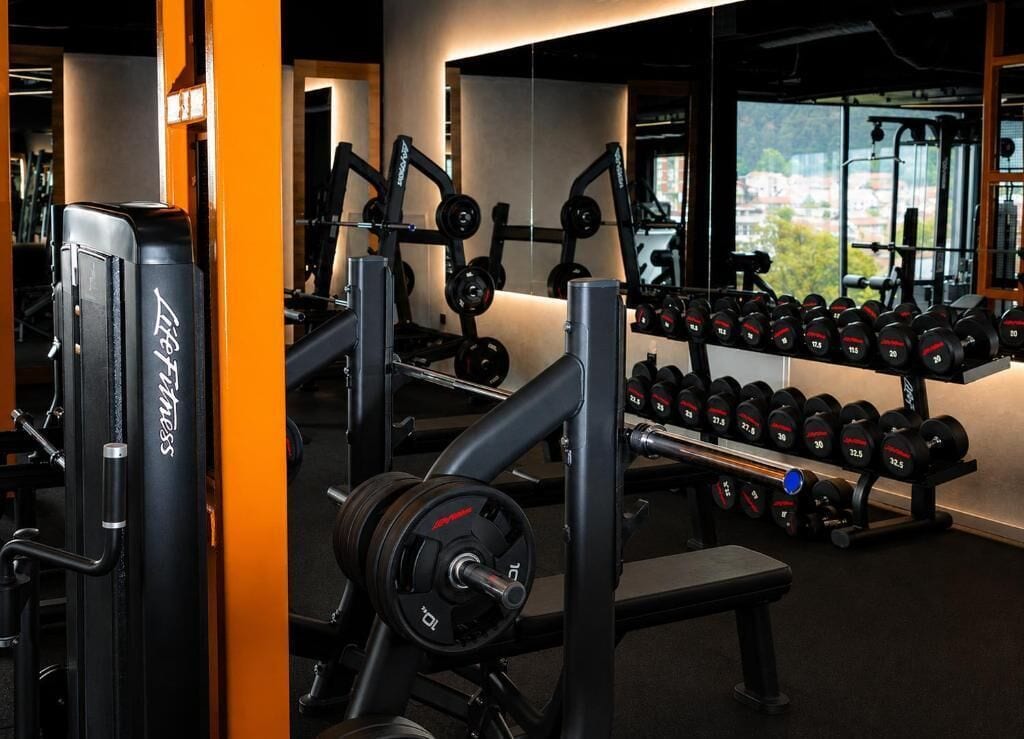 A gym with weightlifting equipment, dumbbells, and benches.