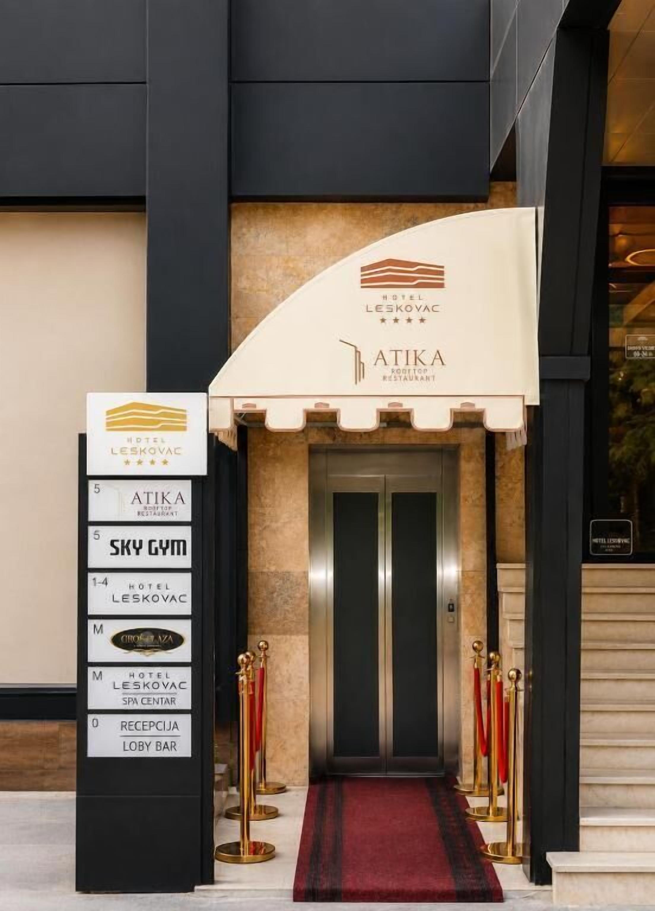 A hotel entrance with a reception desk, a staircase, and a sign indicating amenities like a gym and spa center.