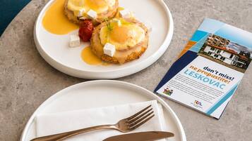 Two plates of food on a table with a brochure and cutlery.