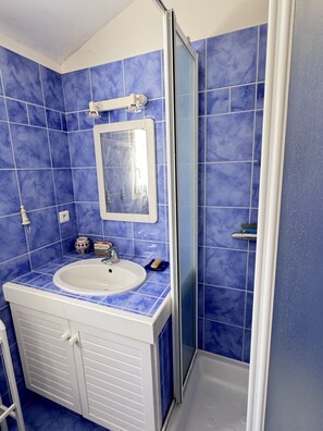 Een badkamer met een wastafel, spiegel en douche.