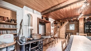 Cocina rústica con vigas de madera, estufa y zona de comedor con taburetes.