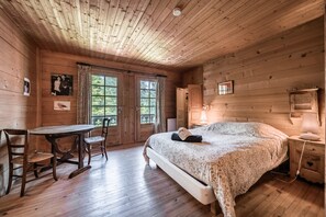 Ein Schlafzimmer einer Holzhütte mit einem Bett, einem Tisch, Stühlen und einem Fenster.
