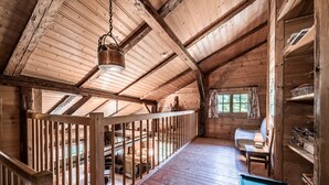 Una cabaña de madera con mesa de billar, lámpara colgante y ventana con cortinas.