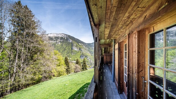 Una cabaña de madera con balcón que da a un paisaje montañoso.