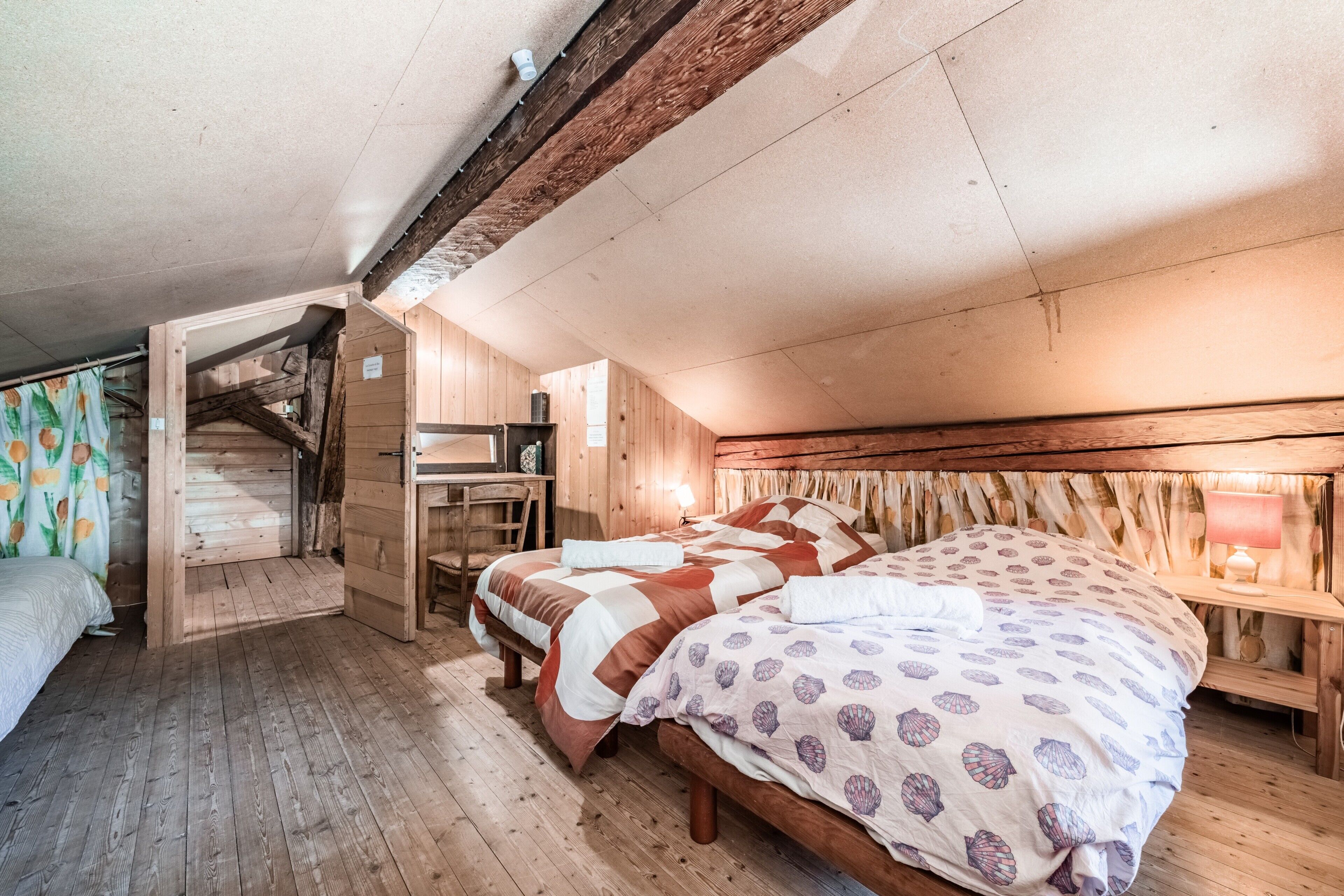 Een houten kamer met een bed, een bureau en een trap.