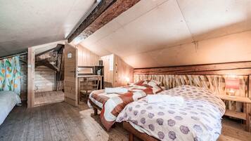 Een houten kamer met een bed, een bureau en een trap.