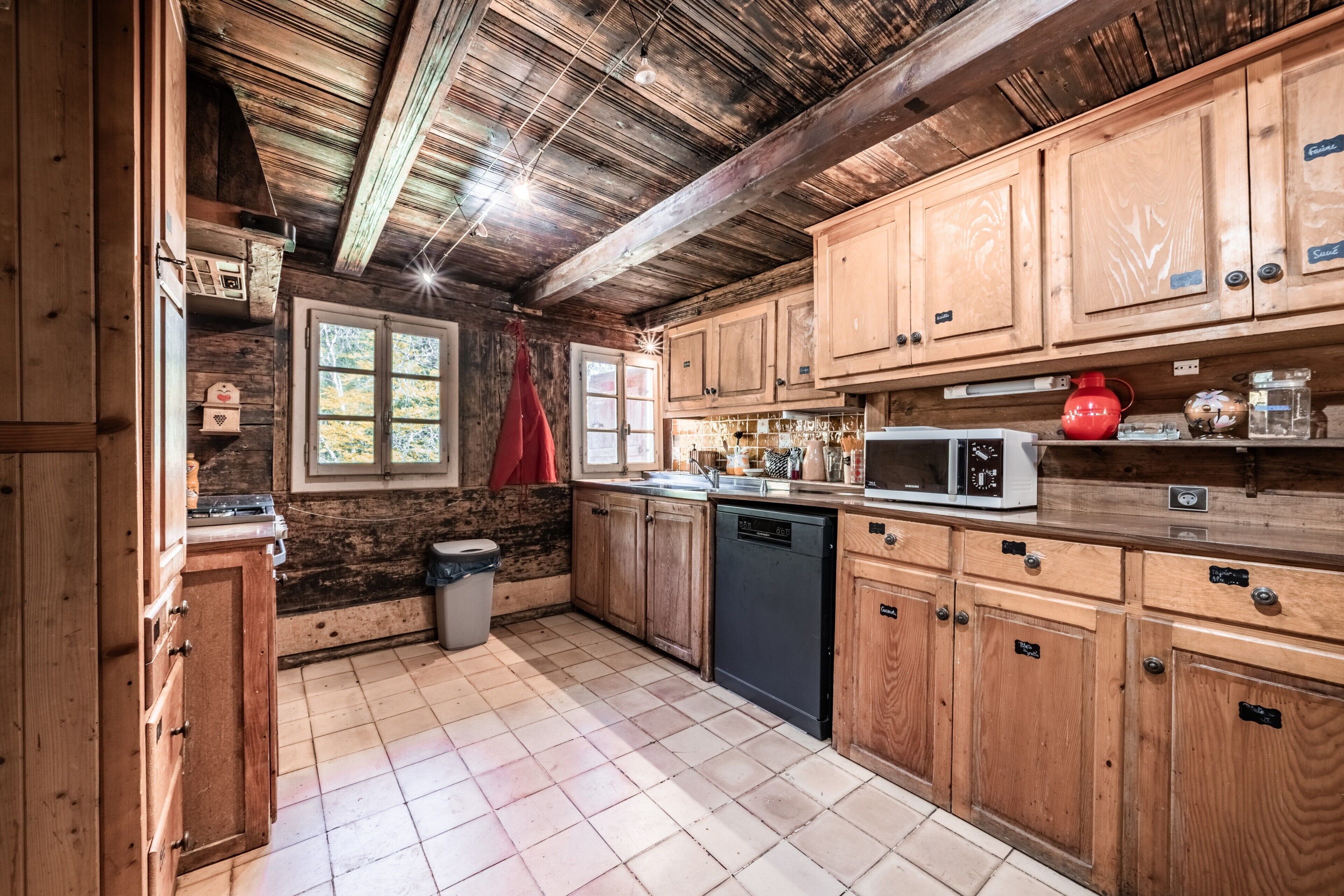 Une cuisine rustique avec des meubles en bois, un four à micro-ondes et une fenêtre donnant sur les arbres.