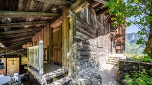 Una cabaña rústica de madera con un porche, escalones de piedra y vistas a las montañas.