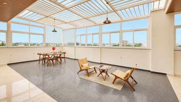 A spacious room with a high ceiling, large windows, and a view of the cityscape.