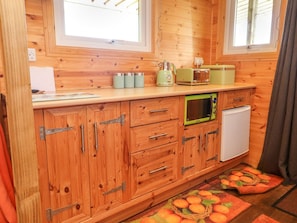 Eine kleine Küche mit Holzausstattung, einer Mikrowelle, einem Toaster und einem kleinen Kühlschrank.