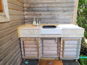 Eine Holzhütte mit eingebautem Spülbecken und Stauraumschränken.