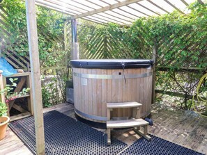 Ein hölzernes Whirlpool mit Metallrahmen, einer Holzterrasse und einer Pergola.