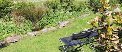 A grassy outdoor area with a metal chair and a stone pathway.