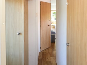 Ein Flur mit Holztüren, einem sichtbaren Bett und einem Koffer auf dem Boden.