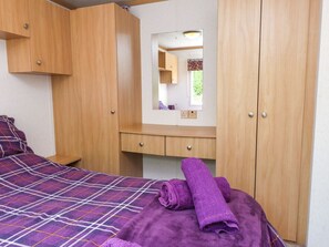 Ein Schlafzimmer mit einem Bett, einem Holzschrank, einem Spiegel und einem kleinen Schreibtisch.