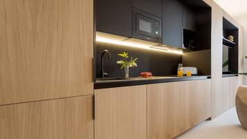 A modern kitchen with wooden cabinets, a black countertop, a microwave, and a vase with flowers.