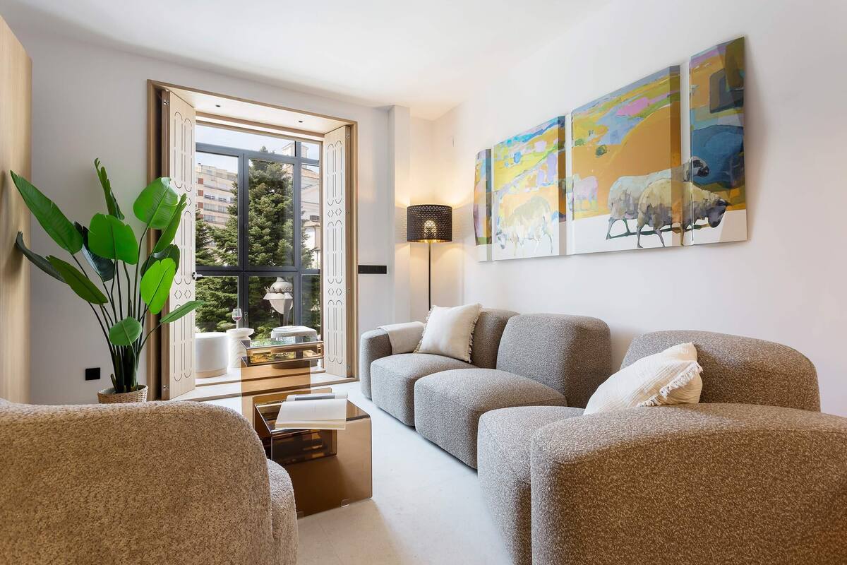 Een moderne woonkamer met een bank, een salontafel, een vloerlamp en een groot raam.