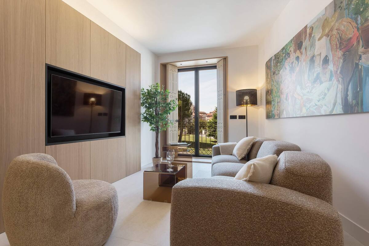 Een moderne woonkamer met een flatscreen televisie, een groot schilderij en uitzicht op het omliggende landschap.