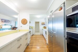 A kitchen with white cabinets, a stainless steel refrigerator, and wooden flooring.