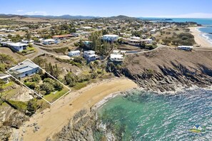 An aerial view of a coastal residential area with houses, a beach, and a rocky shoreline. - Silver Waters - Where Your Private Beach Awaits (Zilzie)