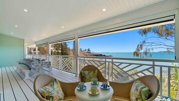 A covered outdoor seating area with a table and chairs, overlooking a scenic view.