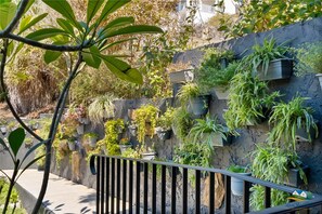 Un balcon doté d’une balustrade en métal, agrémenté de différentes plantes en pot et de verdure.