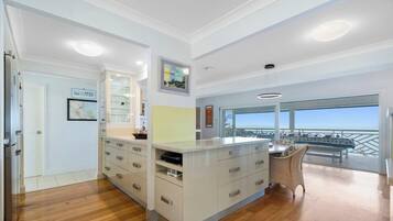 A modern kitchen with a large island, a dining area with a view, and a balcony with a railing.
