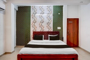 A bedroom with a bed, a red headboard, a wooden door, and patterned wallpaper. - Hotel O Aura Mall Bhopal (Bhopal)