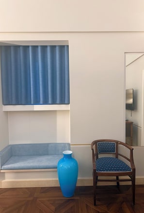 A room with a blue sofa, a blue vase, and a wooden chair. - Hotel Fiore di Maggio – Boutique Suites in Downtown Matera (Matera)