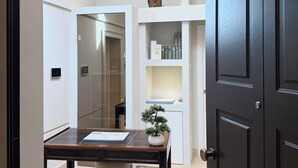 Et moderne interiør med en mørk trædør, et skrivebord med en plante og et gulv med mønster.
