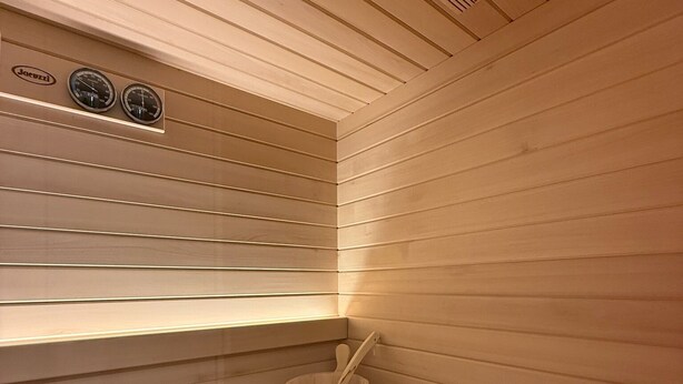 En sauna med trælameller, en spand med træskeer og en varmeovn.