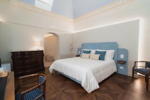 A bedroom with a bed, a wooden dresser, a chair, and a desk. - Hotel Fiore di Maggio – Boutique Suites in Downtown Matera (Matera)