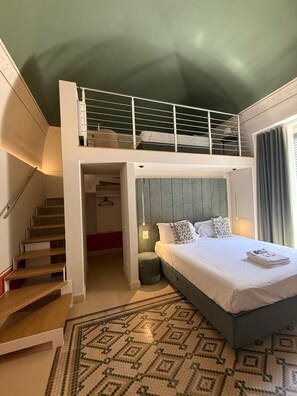 A room with a bunk bed, a staircase, and a patterned rug.