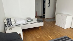 A modern bedroom with a bed, bedside table, lamp, and a white dresser. - Mälartorget - Stay Smart (Västmanlands län)