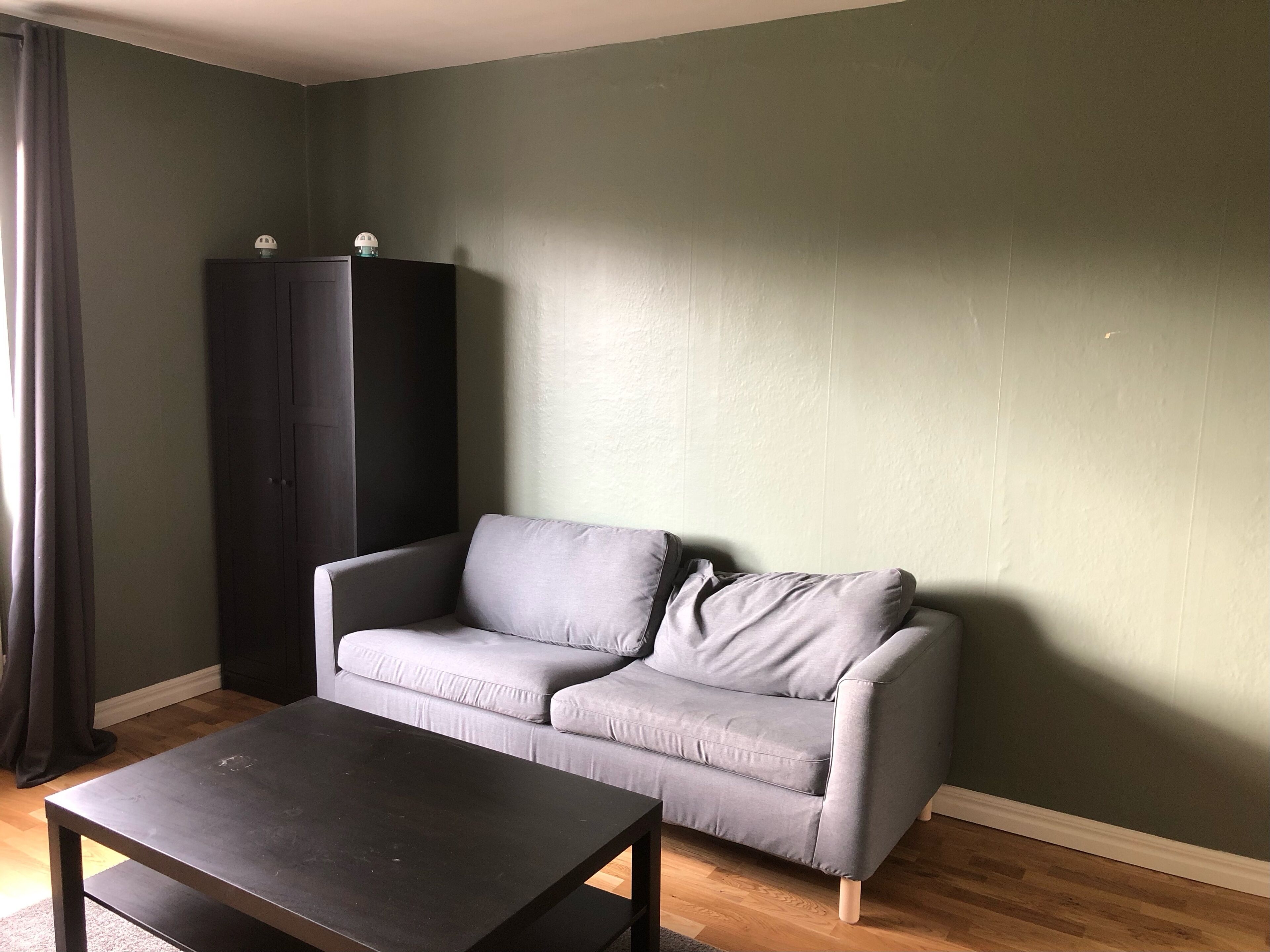 Una sala de estar con un sofá gris, una mesa de madera oscura y un armario de madera oscura.