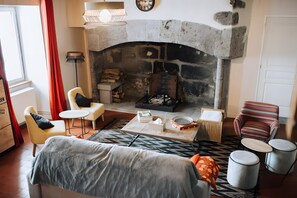 A cozy living room with a stone fireplace, a sofa, a chair, a small table, and a patterned rug.