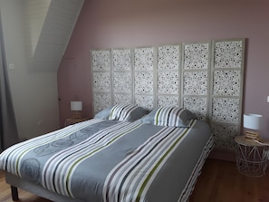 Een slaapkamer met een bed, een decoratief hoofdbord, twee nachtkastjes en een bijzettafeltje.
