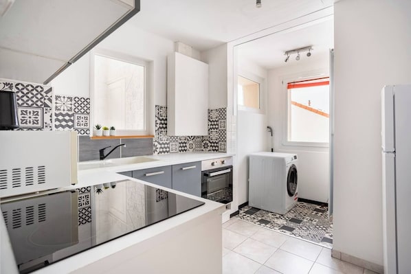 A compact kitchen with a washing machine, a sink, and a window with a view.