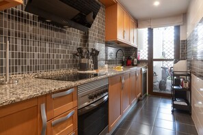 Eine moderne Küche mit Granit Arbeitsplatten, Edelstahlgeräten und Holzschränken.
