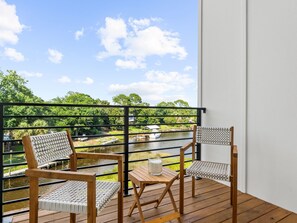 Ein Balkon mit zwei Korbstühlen, einem kleinen Holztisch und einer Kerze.