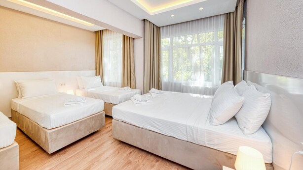 A hotel room with two beds, a large window with curtains, and a modern ceiling design. - Port Apart Hotel (Istanbul)