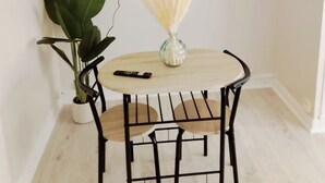 A small dining area with a round table, a potted plant, a vase with dried flowers, a remote control, and a mounted TV on the wall. - A Cozy Retreat in the Heart of Boulogne-sur-Mer (Boulogne-sur-Mer)