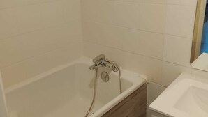 A bathroom with a bathtub, a sink, and a mirror. - A Cozy Retreat in the Heart of Boulogne-sur-Mer (Boulogne-sur-Mer)