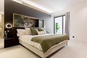 A modern bedroom with a large bed, a wall-mounted artwork, a bedside table, and a window with curtains. - Exclusive Apartment in Valladolid Solanilla I (Valladolid)