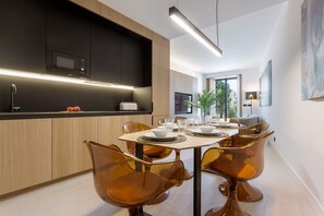 Una cucina moderna con elettrodomestici integrati, un'area pranzo con tavolo imbandito per quattro persone e vista sull'esterno.