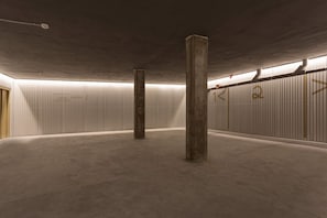 A spacious indoor area with concrete pillars, corrugated metal walls, and a ceiling with exposed beams. - Elegant 3BD Apartment in Valladolid Solanilla II (Valladolid)